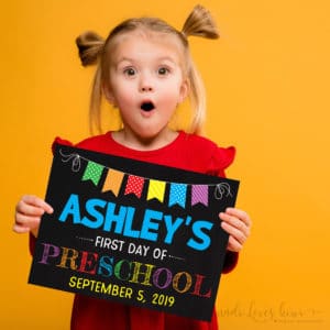 girl holding chalkboard first day of school sign